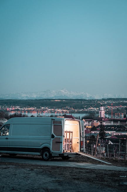 A white moving van parked outside a property with the side panel displaying the company name 'Moving Company' and the slogan 'Local & Long Distance.' The vehicle is positioned on a paved area, with th