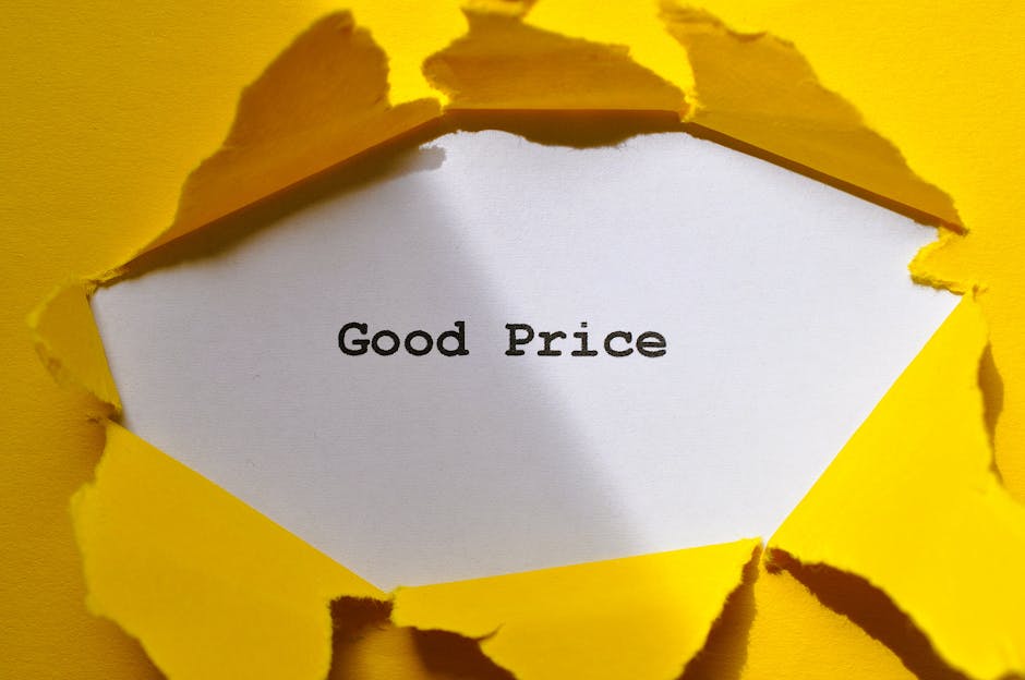 A piece of bright yellow paper is torn open to reveal a white interior with the words 'Good Price' printed in black text. The torn edges of the paper are irregular and jagged, exposing the white layer beneath. The background surrounding the torn paper is also yellow, creating a high contrast that draws attention to the message. This image is relevant to house removals and moving services provided by Man with Van Woodside, illustrating a focus on cost transparency and affordable moving options during home relocation or furniture transport processes, with the torn paper symbolising uncovering value or good deals in the context of packing and moving logistics.